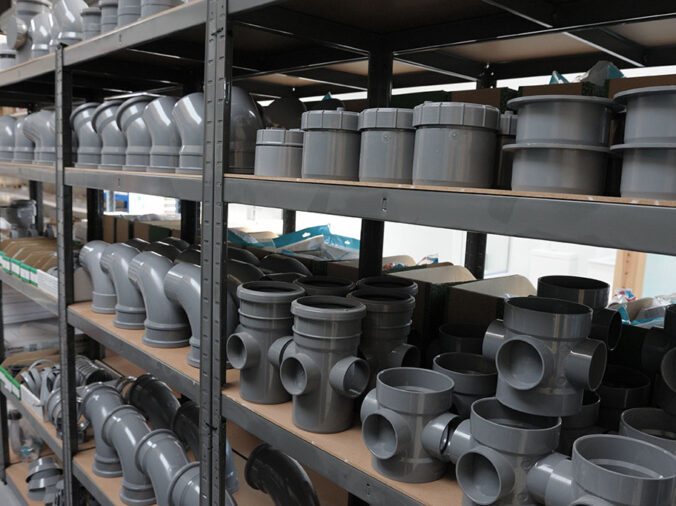 grey PVC plumbing connectors and fittins on the shelf of a plumbing supply warehouse